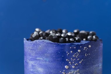 Yaban mersinli ve gümüş kandurinle kaplı mavi krem peynirli doğum günü pastası. Mavi arkaplanda kozmik pasta ya da uzay temalı pasta.