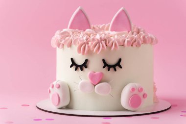 Kedi şeklinde şirin bir doğum günü pastası. Pembe arka planda pembe krem kürkle süslenmiş mastik kulakları ve pençeleri var. Kedileri seven küçük bir kız için sevimli bir pasta.