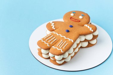 Geleneksel Noel ballı zencefilli adam pastası. Mavi pastel arka planda kar taneleri gibi üzerine pudra şekeri serpiştirilmiş tereyağlı kek. Mutlu Noeller ve mutlu yıllar konsepti.