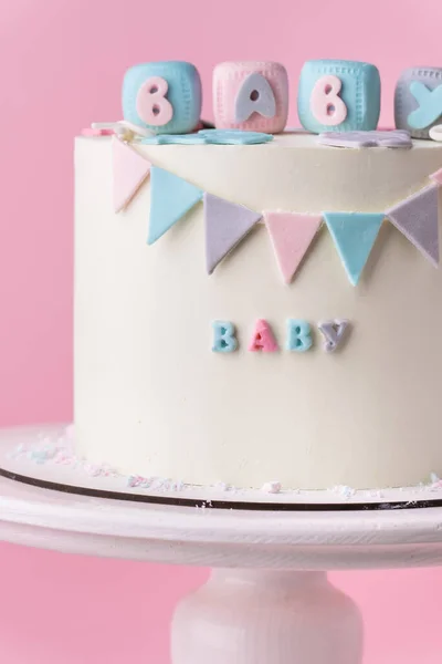 Baby shower party cake with white chocolate frosting. Guess the gender of the upcoming child. He or She cake. Reveal the gender of the unborn baby. Blue or pink sponge bisquit inside. Pink background