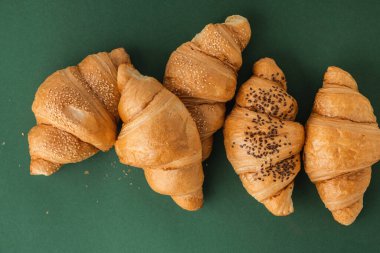 Yeşil arka planda taze pişmiş kruvasan yatıyordu. Ücretsiz metin için fotokopi alanı olan geleneksel Fransız pastası