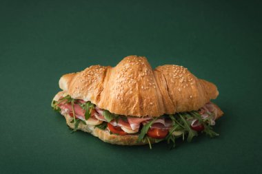 İber jambonu, domates ve koyu yeşil arka planda salata ile taze pişmiş kruvasan. Ücretsiz metin için kruvasan kopyalama alanı ile modelle