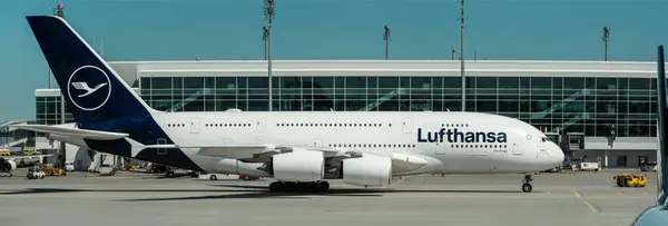 Stock image Munich, Germany-April 27, 2024: Panorama view of Airbus A380 with Lufthansa airlines livery at Munich Airport. Big passenger aircraft next to terminal building and airport infrastructure on sunny day