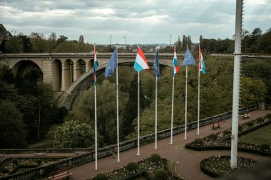 Arka planda Adolphe Köprüsü varken, Lüksemburg ve Avrupa Birliği Bayrakları 'nın görüntüsü rüzgarda uçuşuyor. Lüksemburg Şehri Lüksemburg Grandükü 'nün başkenti.