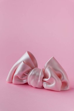 Pembe arka planda makarna şekerinden yapılmış pembe yay yakın çekim. Küçük bir kız için ev yapımı kek süslemesi.