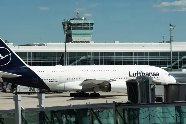 stock image Munich, Germany - April 27, 2024: Airbus A380 of Lufthansa airlines parked at gate of Munich Airport. Big aircraft next to terminal building and airport infrastructure during sunny day.