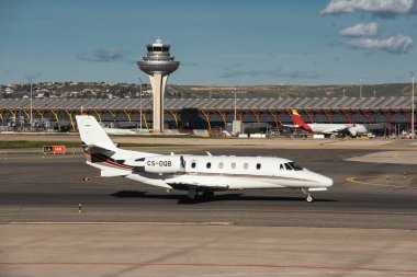 Madrid, İspanya - 2 Şubat 2024: Şatafatlı Cessna 560XL Citation XLS NetJets Europe Airlines iş jetlerinin güneşli bir günde Madrid-Barajas Havalimanı 'nda Hava Trafik Kontrol Kulesi vergilendirmesi