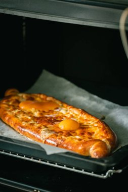 Peynir ve yumurta sarısı ile hazır-yemeye-hazır-yardımcı khachapuri 'nin yakın görüntüsü. Fırında yumuşacık kabuklu yeni pişirilmiş geleneksel Gürcü mutfağı.