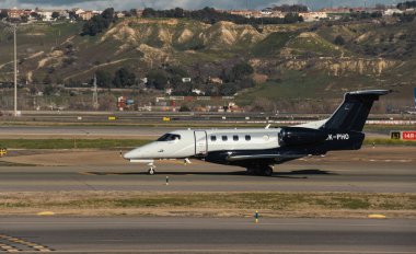 Madrid, Spain - February 02, 2024: Luxury Embraer Phenom 300 business jet aircraft of Atmospherica Aviation Airlines taxing in Madrid-Barajas Airport during sunny day clipart