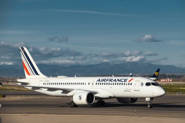Madrid, İspanya - 12 Şubat 2024: Büyük Yolcu Airbus A220-300 Air France havayolları güneşli bir günde Madrid-Barajas Havalimanı 'ndan ayrılmadan önce Hava Trafik Kontrol Kulesi' nin yanında vergilendiriliyor.