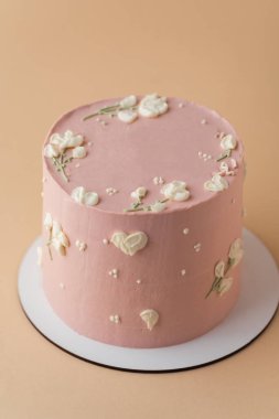 Güzel bir doğum günü pastası. Şeftali renginde çikolata kremalı. Bej rengi pastel arka planda.