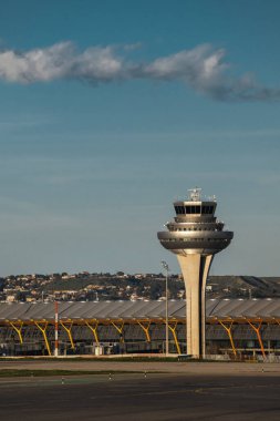 Madrid, İspanya - 12 Şubat 2024: Güneşli bir günde Madrid-Barajas Havaalanı 'ndaki terminal binasının yakınındaki büyük ve modern hava trafik kontrol kulesi.