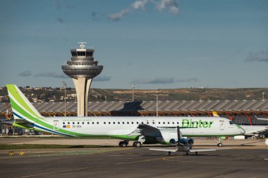 Madrid, İspanya - 12 Şubat 2024: Binter Canarias 'ın Yolcu Embraer E195-E2 uçağı güneşli bir günde Madrid-Barajas Havalimanı' ndaki hava trafik kontrol kulesinin yanında havalanmadan önce vergi indiriyor.
