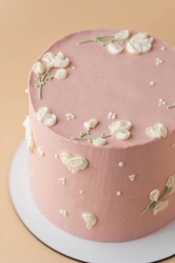 Güzel bir doğum günü pastası. Şeftali renginde çikolata kremalı. Bej rengi pastel arka planda.