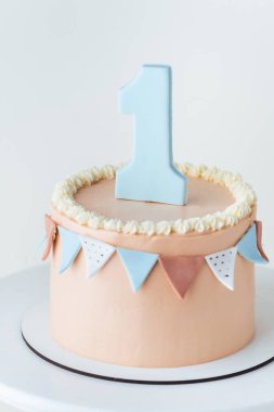 Şeftalili doğum günü pastası ya da üzerinde bir numaralı yenilebilir fondöten bulunan bej çikolata süslemeli. Küçük kız ya da oğlan bir yaşında kutlama yapıyor. İlk doğum günü partisi. Beyaz arkaplan