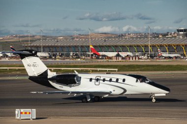 Madrid, Spain - February 02, 2024: Luxury Cessna 650 Citation VI business jet aircraft of JetStream Airlines with black and white livery taxing in Madrid-Barajas Airport during sunny day clipart