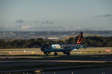 Madrid, Spain - February 02, 2024: Big passenger Airbus A320 aircraft of Brussels Airlines with Tintin comics Livery taxing by Air Traffic Control Tower in Madrid-Barajas Airport during sunny day. clipart