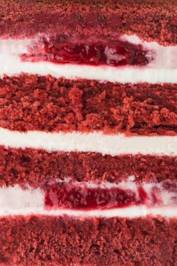 Kırmızı kadife pasta, dokulu arka plan şeklinde kesilmiş. Bisküvi, krem peynir ve kırmızı böğürtlenli kremalı makarna dilimi. Şekerleme dükkanı menüsü için hamur işi arkaplanı