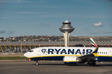 Madrid, İspanya - 02 Şubat 2024: Güneşli bir günde Madrid-Barajas Havaalanı 'ndaki hava trafik kontrol kulesinin yanında düşük maliyetli Ryanair Airlines' ın büyük yolcu uçağı Boeing 737 MAX 8-200