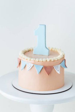 Şeftalili doğum günü pastası ya da üzerinde bir numaralı yenilebilir fondöten bulunan bej çikolata süslemeli. Küçük kız ya da oğlan bir yaşında kutlama yapıyor. İlk doğum günü partisi. Beyaz arkaplan