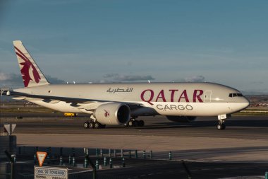 Madrid, İspanya - 12 Şubat 2024: Güneşli bir günde Madrid-Barajas Havalimanı 'ndan ayrılmadan önce Katar Kargo Hava Yolları' nın 777-F 'lik büyük yolcu uçakları hava trafik kontrol kulesinin yanında vergilendiriliyor.