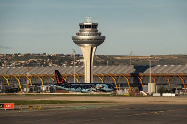 Madrid, Spain - February 02, 2024: Big passenger Airbus A320 aircraft of Brussels Airlines with Tintin comics Livery taxing by Air Traffic Control Tower in Madrid-Barajas Airport during sunny day. clipart