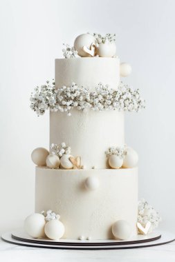 Çikolata küreleri ve çiçeklerle süslenmiş üç katlı güzel bir düğün pastası. Beyaz arkaplan