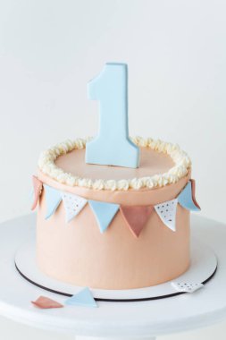 Şeftalili doğum günü pastası ya da üzerinde bir numaralı yenilebilir fondöten bulunan bej çikolata süslemeli. Küçük kız ya da oğlan bir yaşında kutlama yapıyor. İlk doğum günü partisi. Beyaz arkaplan
