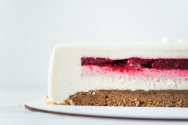 Beyaz arka planda kesilmiş çikolatalı kremalı pastayı kapat. Kırmızı böğürtlen ve beyaz vanilyalı kremalı pasta dilimi ve çikolata jöleli.