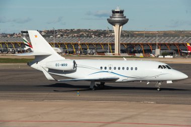 Madrid, İspanya - 02 Şubat 2024: Lüks Dassault Falcon 2000LX Gestair Havayolları iş jet uçağı güneşli bir günde Madrid-Barajas Havalimanı 'nda Hava Trafik Kontrol Kulesi tarafından vergilendiriliyor