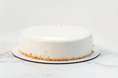 Kurutulmuş waffle kırıntılarıyla süslenmiş ve pürüzsüz çikolata jöleli sade beyaz kremalı pasta. Beyaz mermer arkaplan