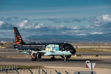 Madrid, İspanya - 2 Şubat 2024: Güneşli bir günde Madrid-Barajas Havalimanı 'nda Hava Trafik Kontrol Kulesi' nden Tintin çizgi romanlarıyla yüklü büyük yolcu Airbus A320 uçağı.