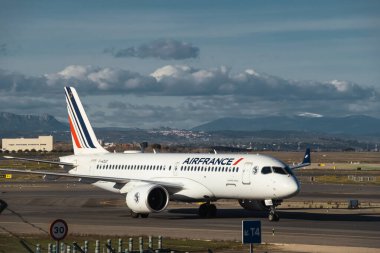 Madrid, İspanya - 12 Şubat 2024: Büyük Yolcu Airbus A220-300 Air France havayolları güneşli bir günde Madrid-Barajas Havalimanı 'ndan ayrılmadan önce Hava Trafik Kontrol Kulesi' nin yanında vergilendiriliyor.