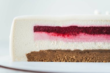 Beyaz arka planda kesilmiş çikolatalı kremalı pastayı kapat. Kırmızı böğürtlen ve beyaz vanilyalı kremalı pasta dilimi ve çikolata jöleli.