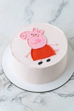 Kyiv, Ukraine - November 09, 2024: Peppa Pig birthday bento cake on the white marble background. Flat lay of the cute cake for a little kid decorated with funny pink pig clipart