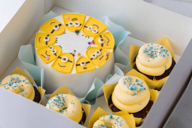 Kyiv, Ukraine - November 18, 2024: Homemade cake with cupcakes set with yellow chocolate frosting in the shape of minion. Character of the animated movie ''Despicable Me'' on top of the birthday cake