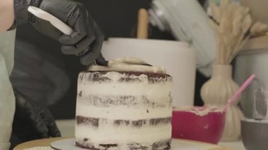 Pasta şefinin pasta tezgahını krem peynirle süslediği pasta poşeti ve spatulayla kapatmasını. Şekerlemecinin pastayı birleştirip süsleme süreci