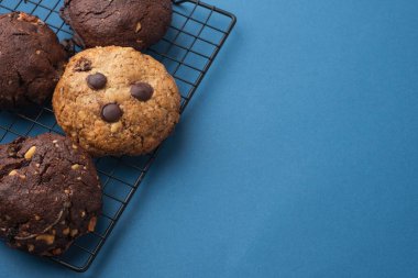 Amerikan yulaf ezmeli kurabiyeler çikolata damlaları ve mavi arka planda kuru üzümler. Şeker tüketimi konsepti. Fotokopi alanı olan hamur işi düzlüğü