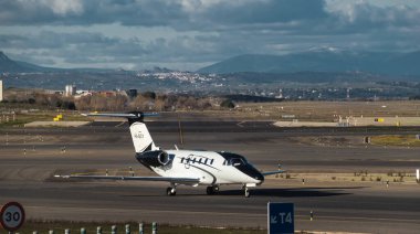 Madrid, Spain - February 02, 2024: Luxury Cessna 650 Citation VI business jet aircraft of JetStream Airlines with black and white livery taxing in Madrid-Barajas Airport during sunny day clipart