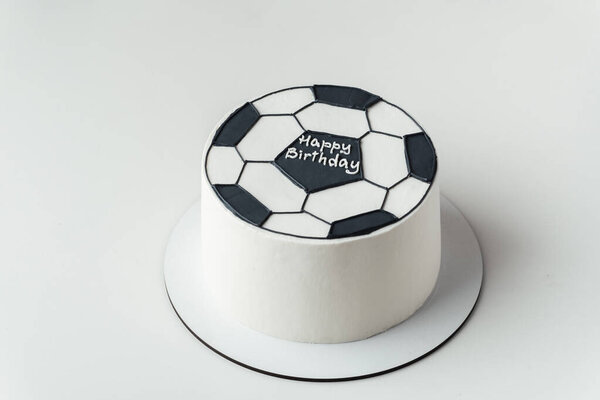 Flat lay of Birthday cake for a football fan in the shape of a soccer ball on the white background