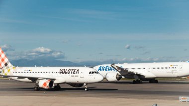 Madrid, Spain - February 02, 2024: Big passenger Airbus A320 aircraft of Volotea Airlines taxing by Boeing 787-900 dreamliner aircraft of Air Europa airlines in Madrid-Barajas Airport clipart