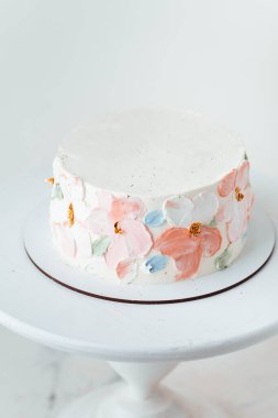 Renkli krem peynirli çiçeklerle süslenmiş beyaz çikolatalı güzel bir pasta. Beyaz arkaplan