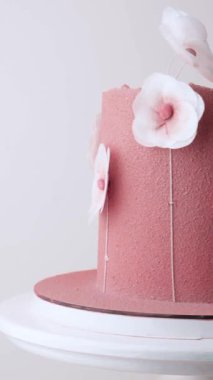 Doğum günü pastası pembe sprey çikolata kaplı ve şeker çiçekleriyle süslenmiş. Güzel yıldönümü ya da beyaz arka planda dönen düğün pastası