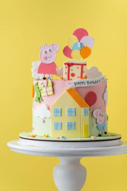 Kyiv, Ukrayna - 27 Şubat 2025: Sarı zemin üzerinde Peppa Pig doğum günü pastası. Komik pembe domuzla süslenmiş küçük bebek için şirin bir pasta.