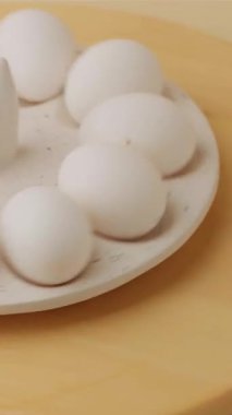 Beyaz Paskalya tavuğu yumurtaları bayram tepsisinde dönüyor. Ahşap arkaplan
