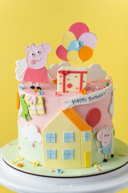 Kyiv, Ukrayna - 27 Şubat 2025: Sarı zemin üzerinde Peppa Pig doğum günü pastası. Komik pembe domuzla süslenmiş küçük bebek için şirin bir pasta.