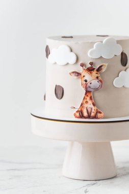 Beyaz arka planda yenilebilir zürafayla süslenmiş bej çikolatalı şirin Afrika tarzı doğum günü pastası..