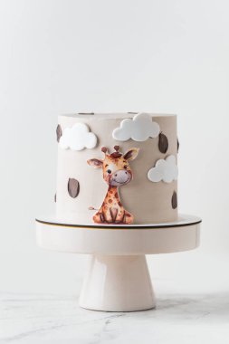 Beyaz arka planda yenilebilir zürafayla süslenmiş bej çikolatalı şirin Afrika tarzı doğum günü pastası..