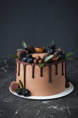 Siyah arka planda yaban mersinli, kurabiyeli ve şekerli çikolatalı pasta. Kahverengi krem peynirli pasta ve üzerinde koyu çikolata damlaları.