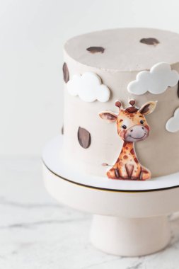 Beyaz arka planda yenilebilir zürafayla süslenmiş bej çikolatalı şirin Afrika tarzı doğum günü pastası..